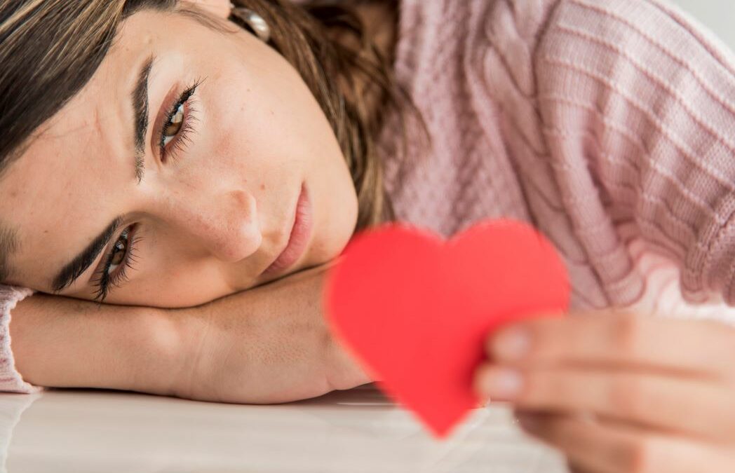 Une femme tenant un coeur rouge en papier dans la main